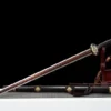 A decorative sword with dragon handle, leaning against a small wooden sword-stand, along with its scabbard below on the floor.