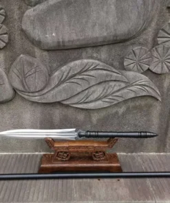 A Chinese spear sword displayed on a wood stand and its handle extension lying on the floor below.