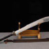 A Chinese warrior sword scimitar, leaning against a small wooden stand, with its leather scabbard on the floor below.