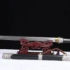 A decorative Damascus short sword displayed on a small wooden stand, with its scabbard below on the floor.