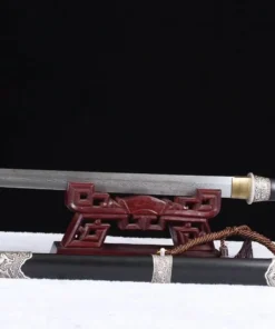 A decorative Damascus short sword displayed on a small wooden stand, with its scabbard below on the floor.
