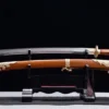 A Dao Chinese sword saber and its decorative scabbard displayed on a small wooden sword stand.