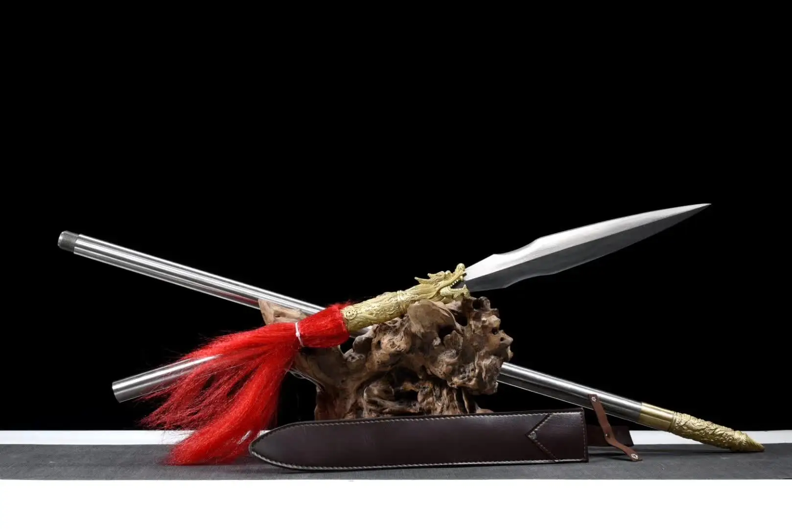 Dragon Spear A dragon spear weapon displayed leaning on a wood log, with its pole handle extension.