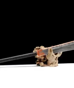 A long handled Jiu Huan Dao sword, displayed on a small wood log.