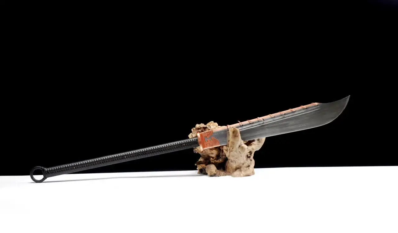 Jiu Huan Dao A long handled Jiu Huan Dao sword, displayed on a small wood log.