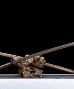 A wooden Miaodao sword and its scabbard leaning against a small wood log.