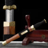 A decorative, traditional dagger sheathed within its wooden sheath, leaning against a wood stand and product highlight above.