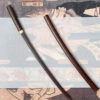 A wooden Katana sword and its scabbard displayed against Japanese art.