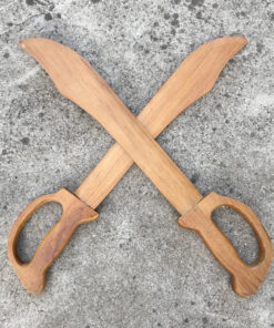 Two wooden practice swords with blades crossed laying on a concrete floor.