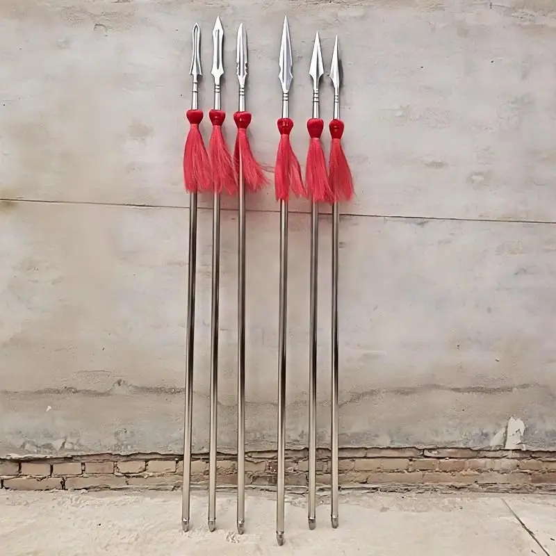 Wushu Spear Six Wushu spear models with red-tassels, leaning against a cement wall.