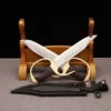 Two Wing Chun butterfly swords with blades crossed, leaning against a wooden stand.