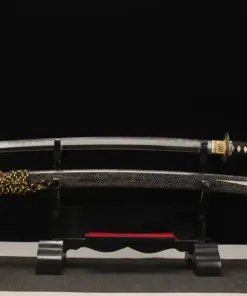 A hand forged Katana saber sword and its scabbard displayed on a small wooden stand.
