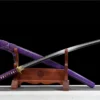 A Katana purple sword displayed crossed against its scabbard, leaning against a small woden stand.