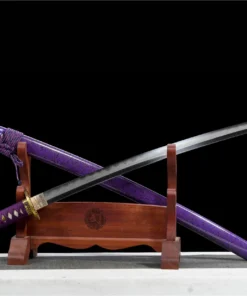 A Katana purple sword displayed crossed against its scabbard, leaning against a small woden stand.