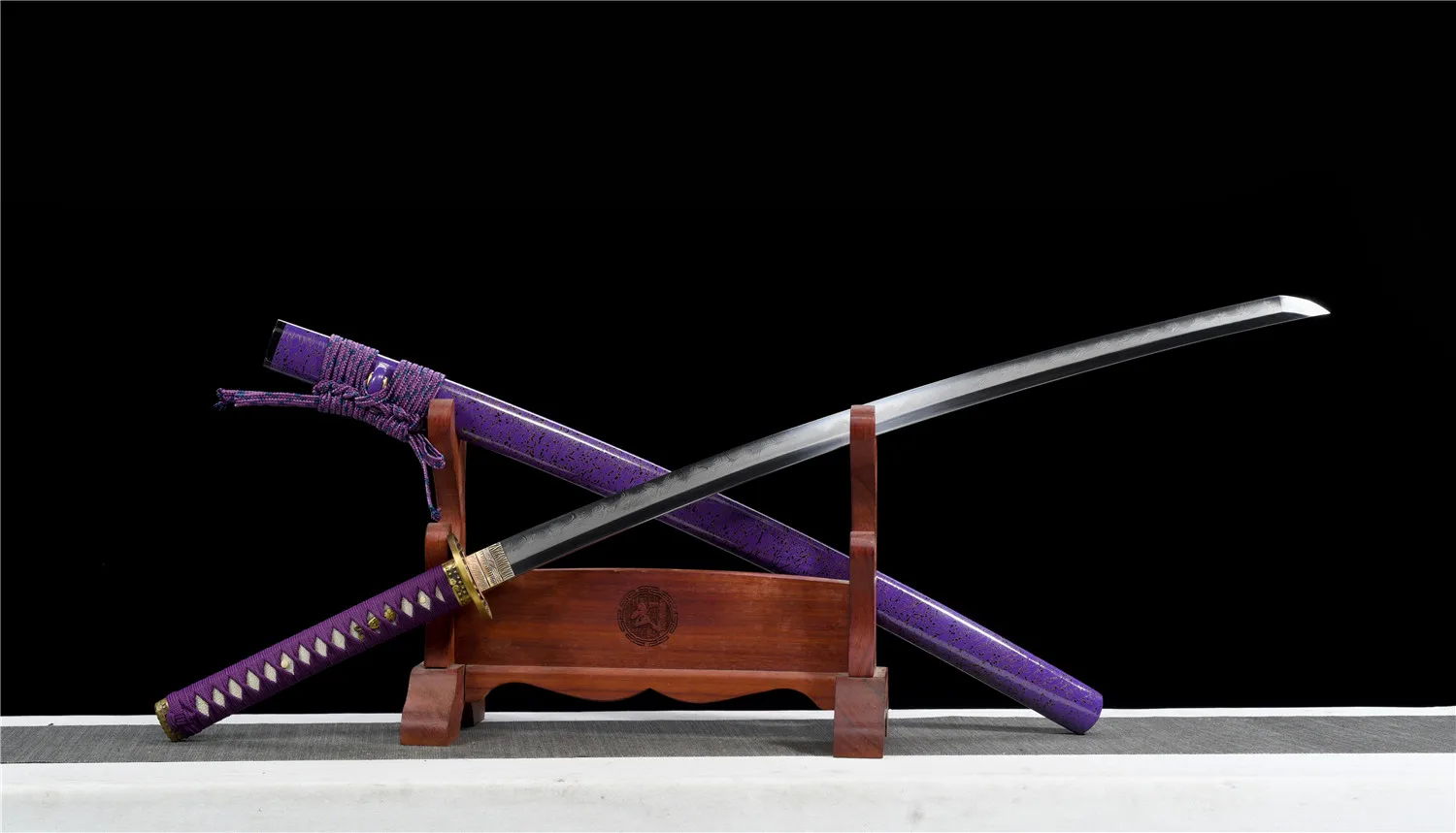 Katana Purple A Katana purple sword displayed crossed against its scabbard, leaning against a small woden stand.
