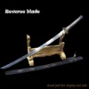 A reverse blade sword leaning against a small wooden stand, with its scabbard below on the floor.