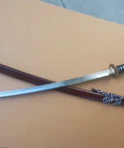 A Japanese Katana sword with a serrated blade crossed over its scabbard.
