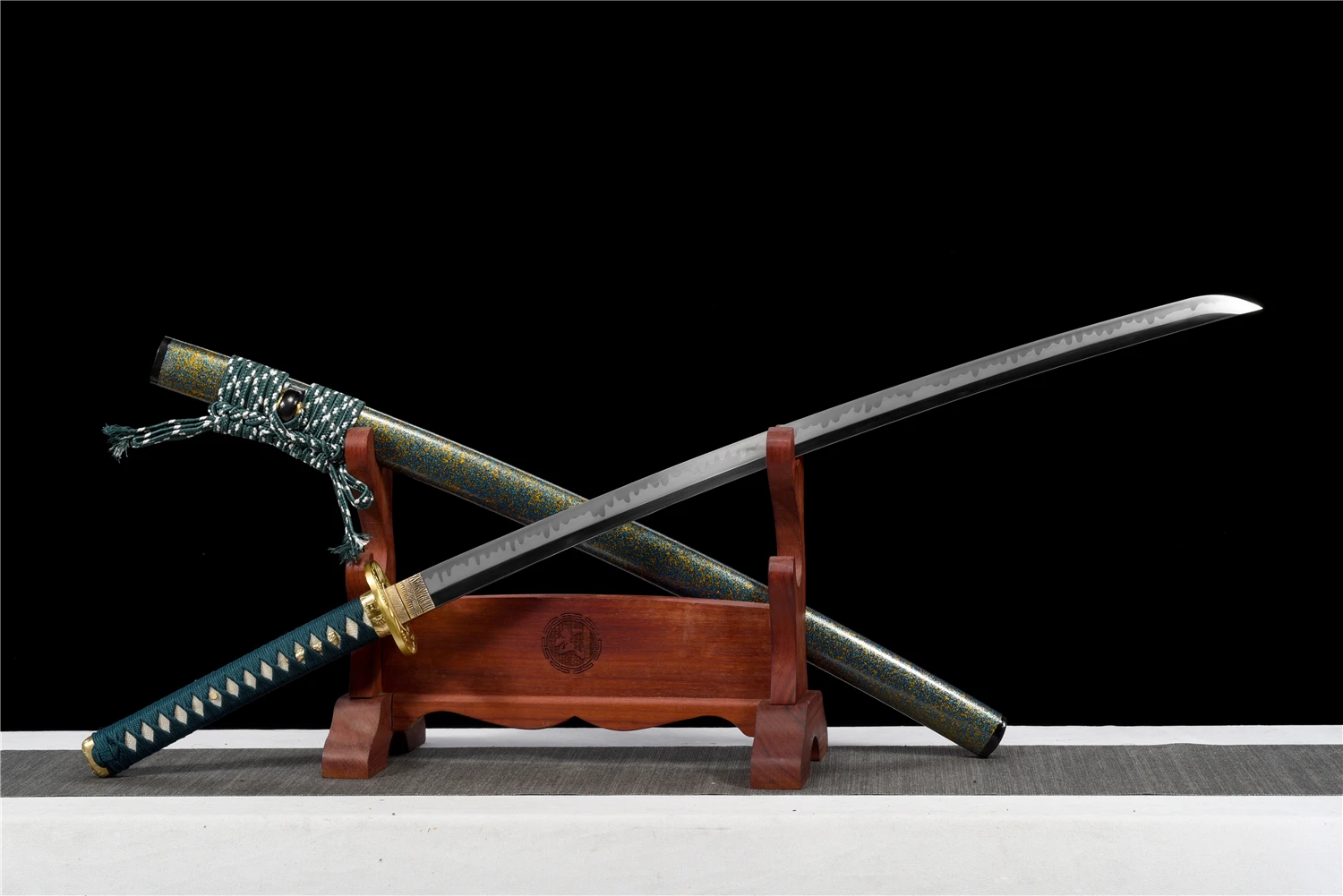 T10 Steel Katana A T10 steel Katana displayed crossed against its scabbard, leaning against a small sword-stand.