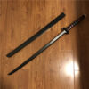 A black colored toy Samurai sword next to its plastic scabbard, lying on a wooden floor.