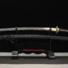 A Japanese Samurai Katana and its black scabbard, displayed on a small wooden stand.