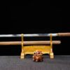 A straight blade, Shikomizue sword and its wooden scabbard displayed on a small wood stand.