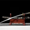 A Tachi Japanese cavalry sword displayed next to its decorative scabbard, on a small wooden stand.