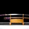 A Japanese folded steel sword Katana, displayed next to its scabbard, on a small wooden sword-stand.