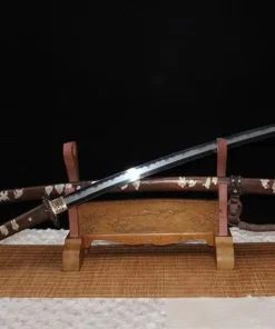 A Japanese Tachi sword displayed next to its decorative scabbard, on a small wooden sword-stand.