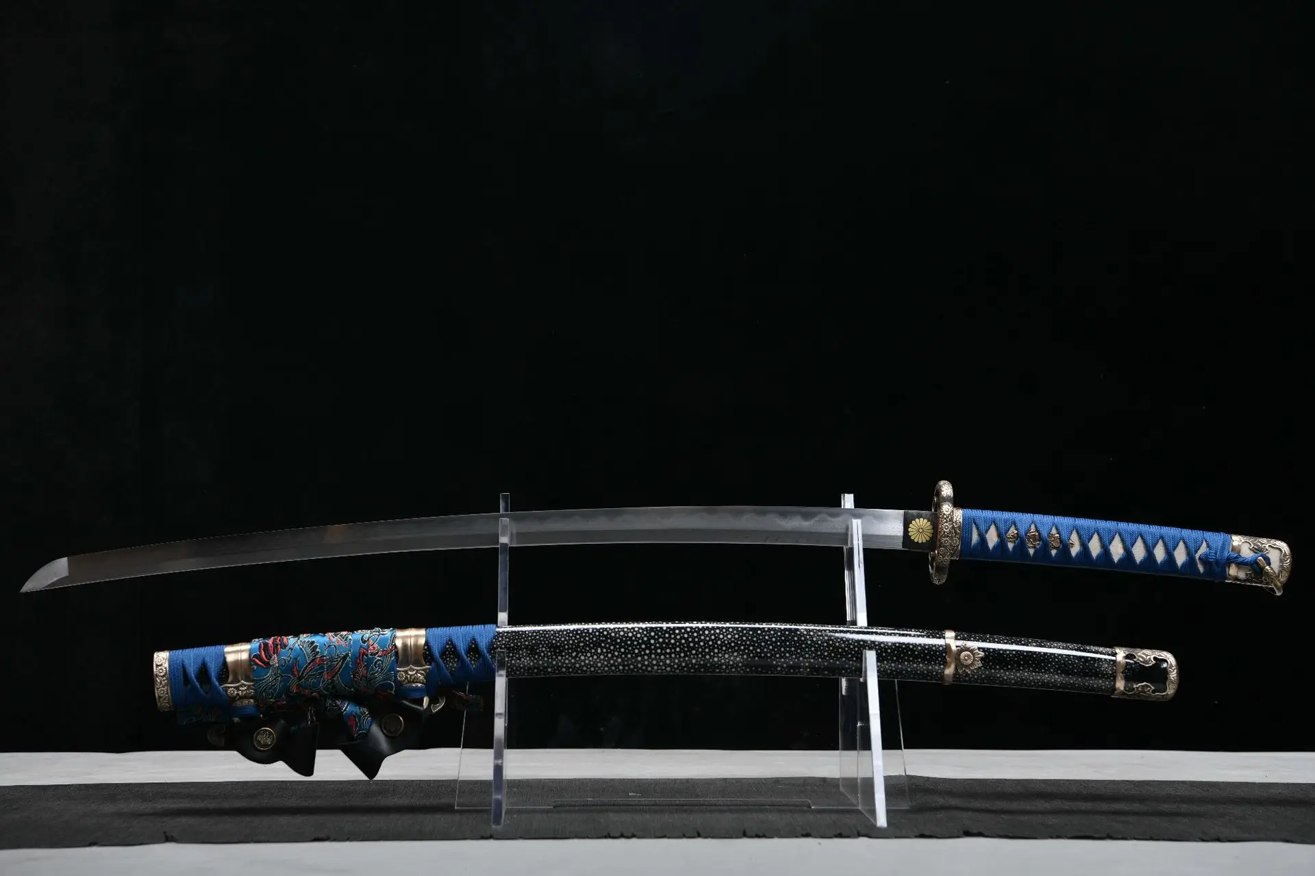 Tachi Japanese Sword A blue Tachi Japanese sword saber, displayed next to its beautiful scabbard, on a small stand.