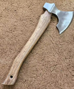 A stainless steel hatchet with a wooden handle displayed lying on a floor.