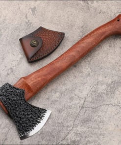 A hand forged bushcraft hatchet with a wooden handle, displayed on a concrete floor next to its small leather axe sheath.