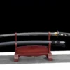 A black Samurai sword and its scabbard displayed on a small wooden stand.