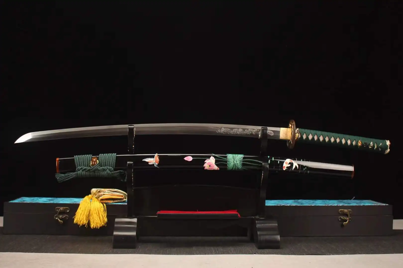 Engraved Katana A Japanese dragon engraved Katana displayed next to its decorative flower & Koi illustrated scabbard, on a small wooden stand.