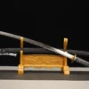 A Japanese Samurai Katana and its scabbrd displayed on a small wooden sword stand.