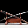 A functional Katana saber sword and its scabbard, leaning against a small wooden stand.