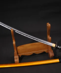 A Iaido Katana displayed on a wooden sword stand, with its orange colored scabbard below on the floor.