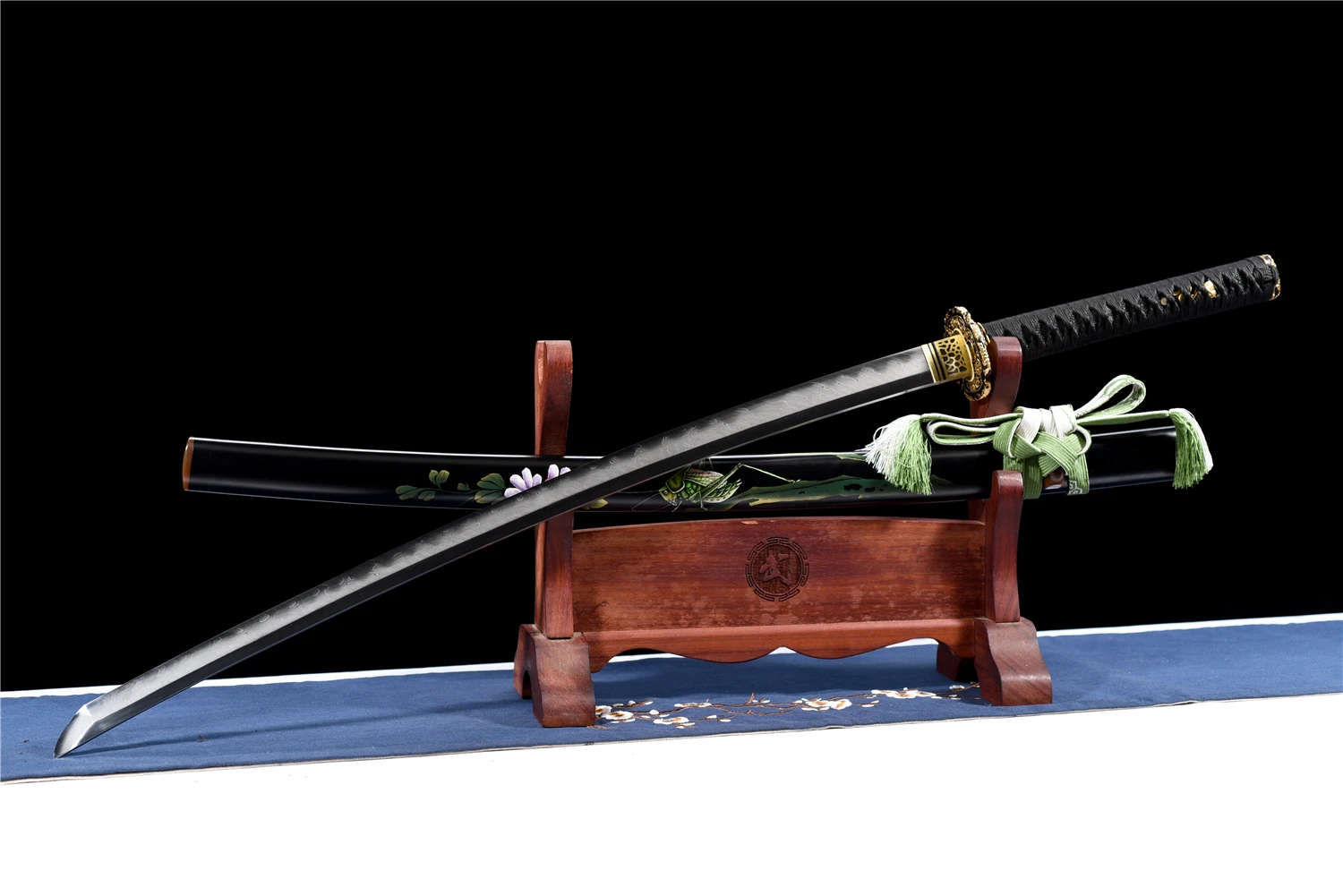 Katana Sword Real Steel A Katana sword real steel weapon, displayed next to its decorative scabbard, on a small wooden stand.