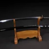 A black tactical Katana and its scabbard displayed on a small wood sword stand.