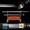A Wakizashi Ninjato sword and its decorative scabbard displayed on a small wooden stand, along with sword highlights both above and below.