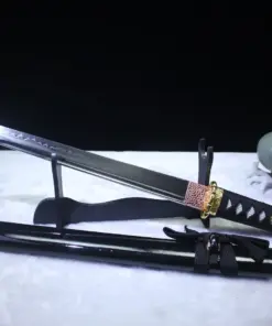 A black Tanto knife displayed leaning against a small wooden stand, with its sheath below on the floor.