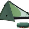 A green colored, single person tent displayed erected, along with a hand holding the packed tent in its carry bag below.