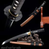 A Samurai Tanto knife displayed leaning against a small wooden stand, alongside its wooden sheath.
