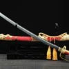 A Kyu Gunto Japanese officer sword, displayed crossed against its decorative scabbard, on a small wooden sword-stand.