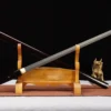 A Shikomizue one piece sword displayed crossed against its wood staff scabbard, leaning against a wooden sword-stand.