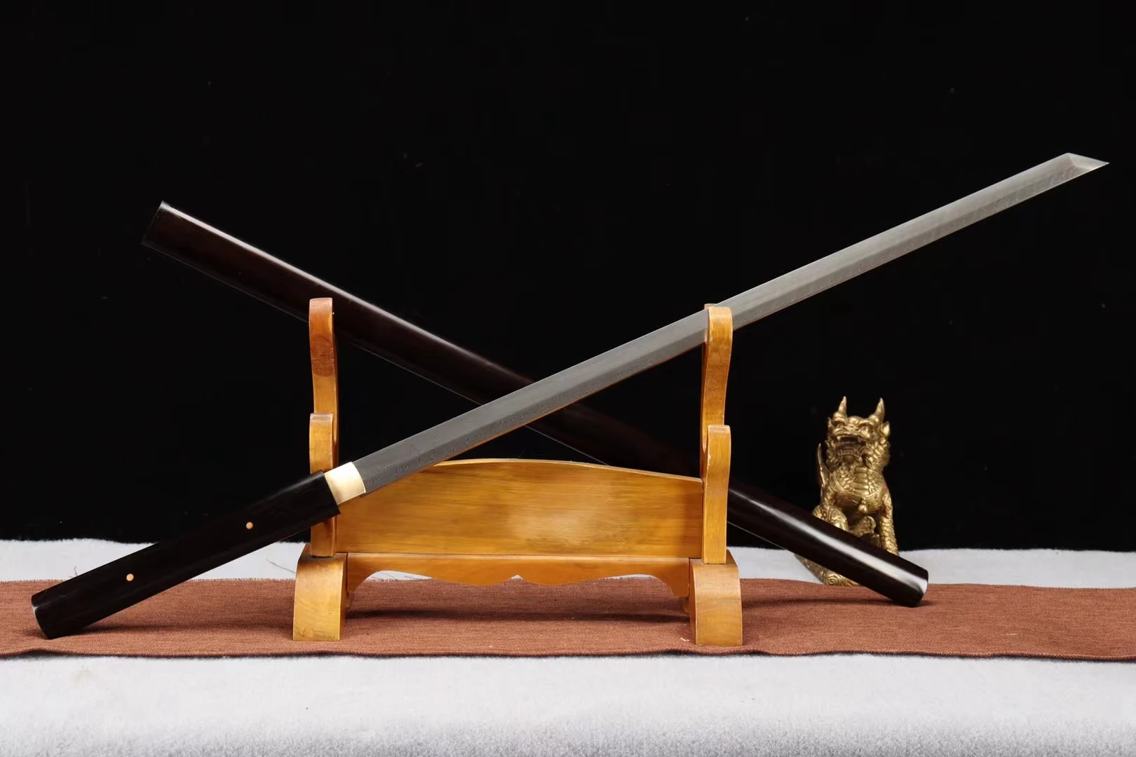 Shikomizue One Piece A Shikomizue one piece sword displayed crossed against its wood staff scabbard, leaning against a wooden sword-stand.