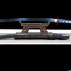 A stainless steel Katana with a blue colored blade displayed on a small wooden sword stand, with its decorative scabbard below on the floor.