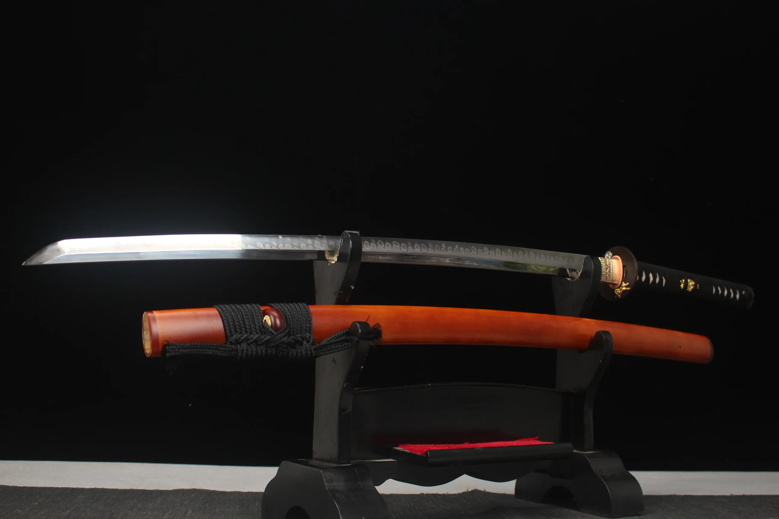 Two Handed Katana A two handed Katana sword and its scabbard displayed on a small wooden sword-stand.