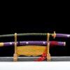 A full sized anime Katana sword displayed alongside its scabbard, on a small wooden sword stand.