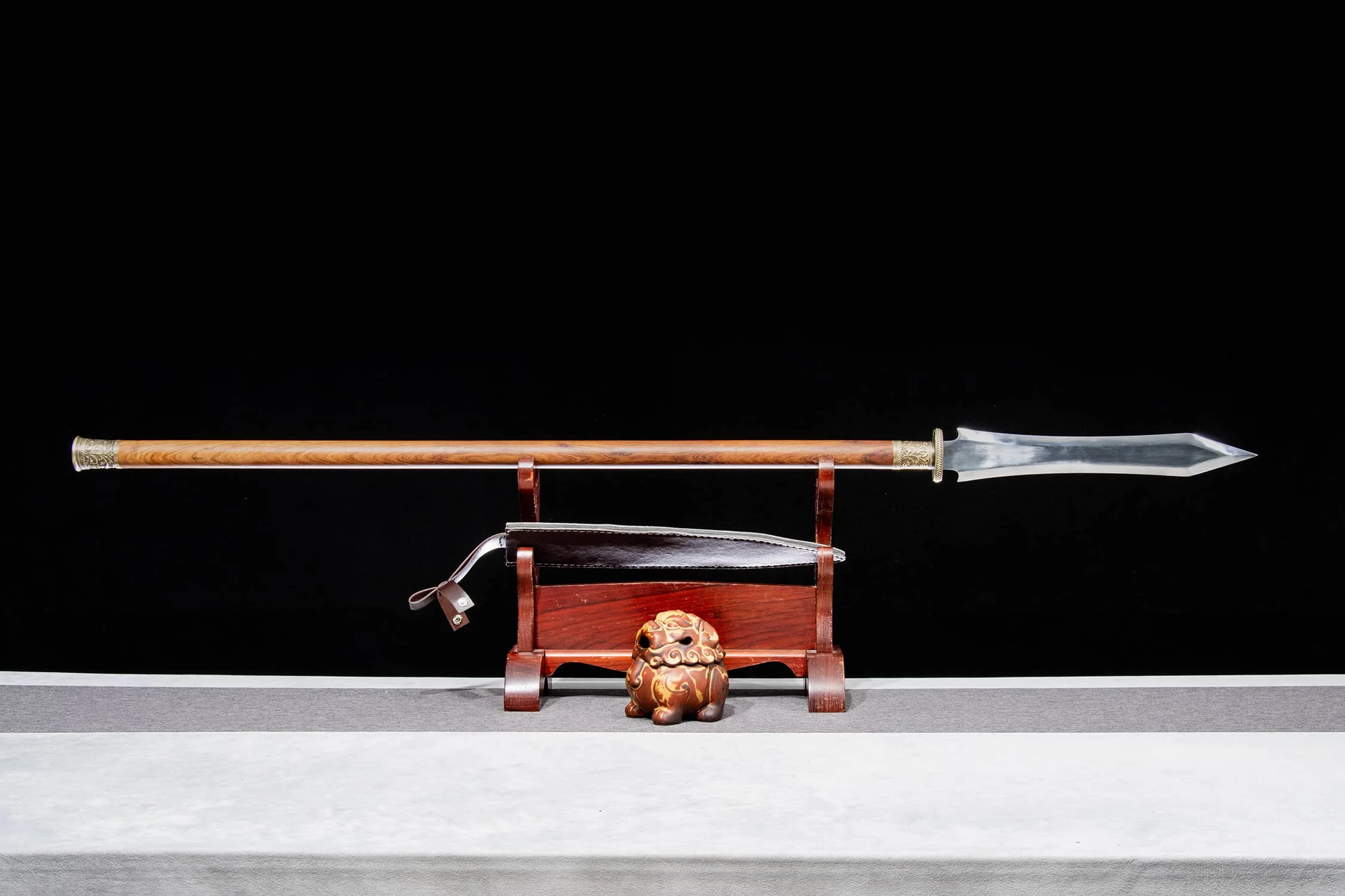 Double Edge Spear A double edge spear weapon, displayed next to its scabbard, on a small woden stand.