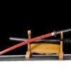 A fake sword with a red plastic blade, displayed alongside its scabbard on a small wooden sword stand.